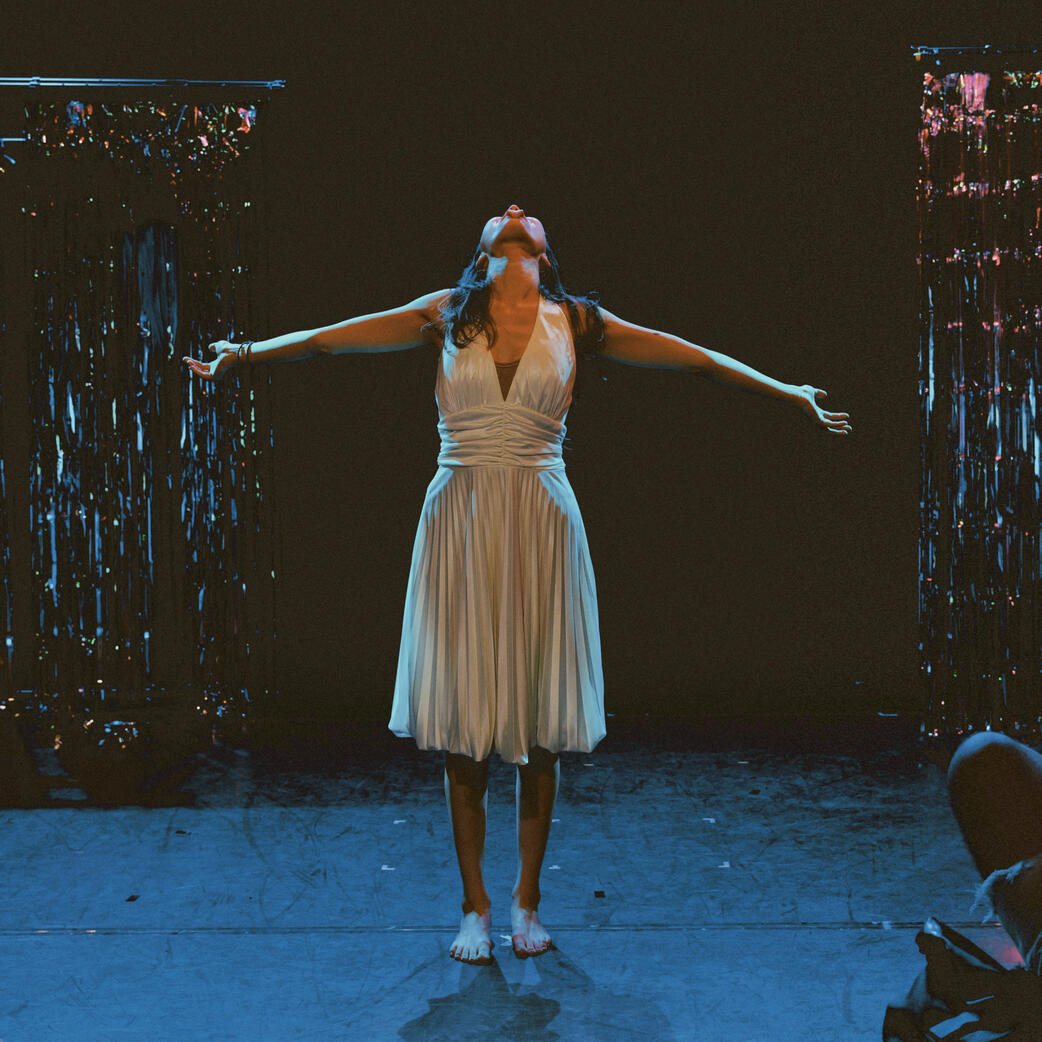 Feride Morçay on stage in CHICKADEE, standing with her arms open