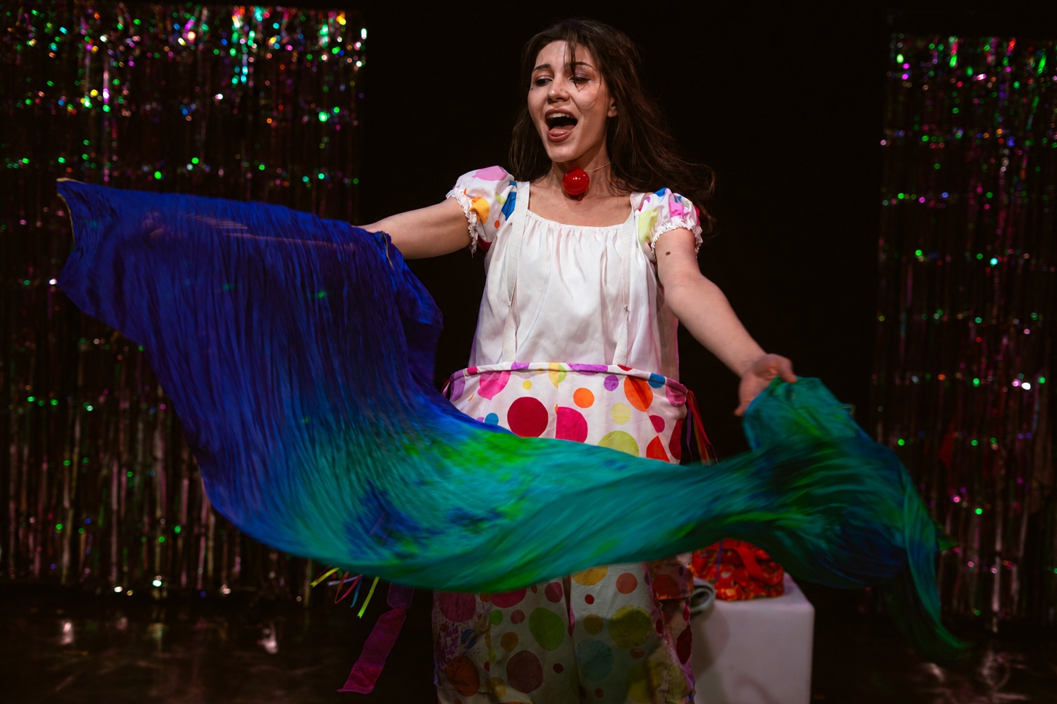 Dahlia joyfully sweeping a blue and green fabric bird across the stage
